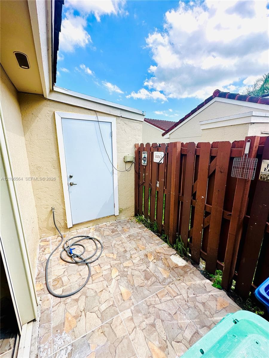 Exterior patio featuring flagstone-style tiling and a wood privacy fence