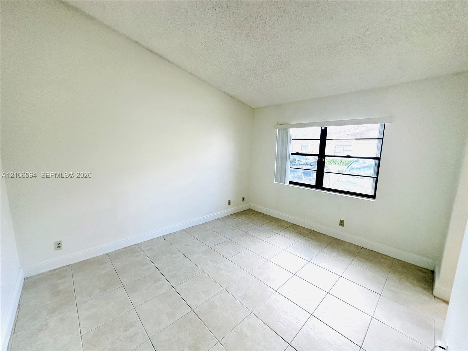 Vaulted ceiling, large-format ceramic tile flooring, and oversized window with black frame