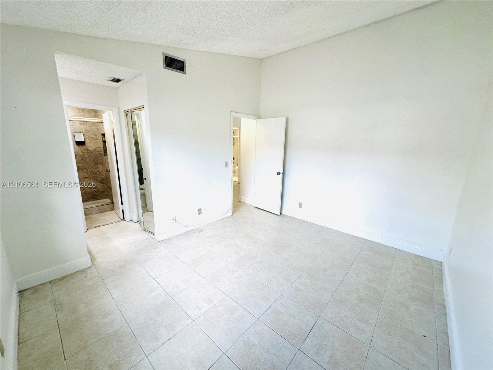 Room featuring vaulted ceilings, light-toned ceramic tile flooring, and a mirrored closet door