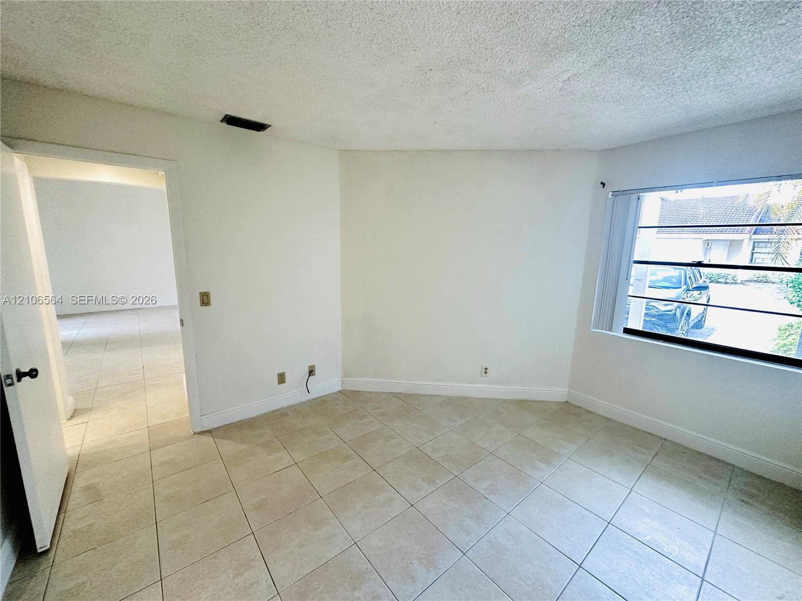 Interior space featuring neutral tile flooring, textured ceiling, and a multi-pane horizontal window
