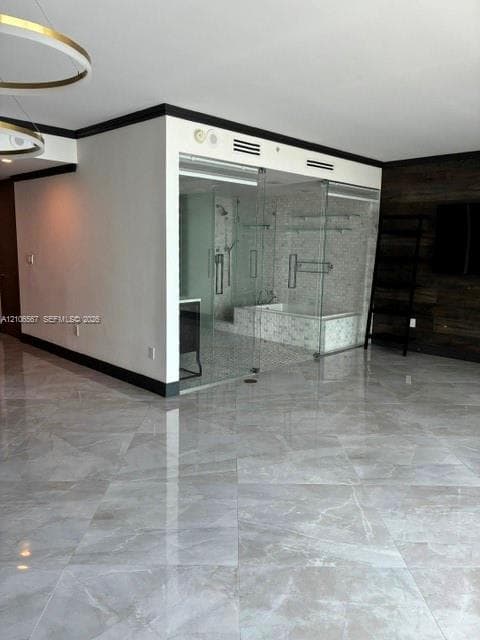 Large-format polished tile flooring, glass-enclosed shower featuring mosaic tile surround, built-in bathtub, and dark wood-finish wall paneling