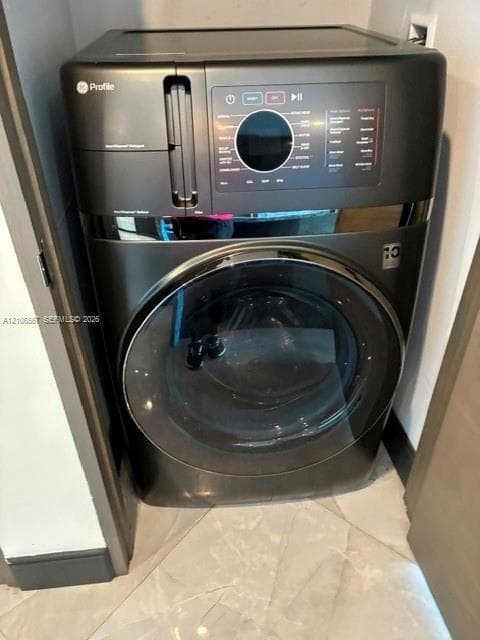 Built-in GE Profile front-load washer featuring a charcoal finish, digital interface, glass door, and integrated detergent dispenser, set against tile flooring