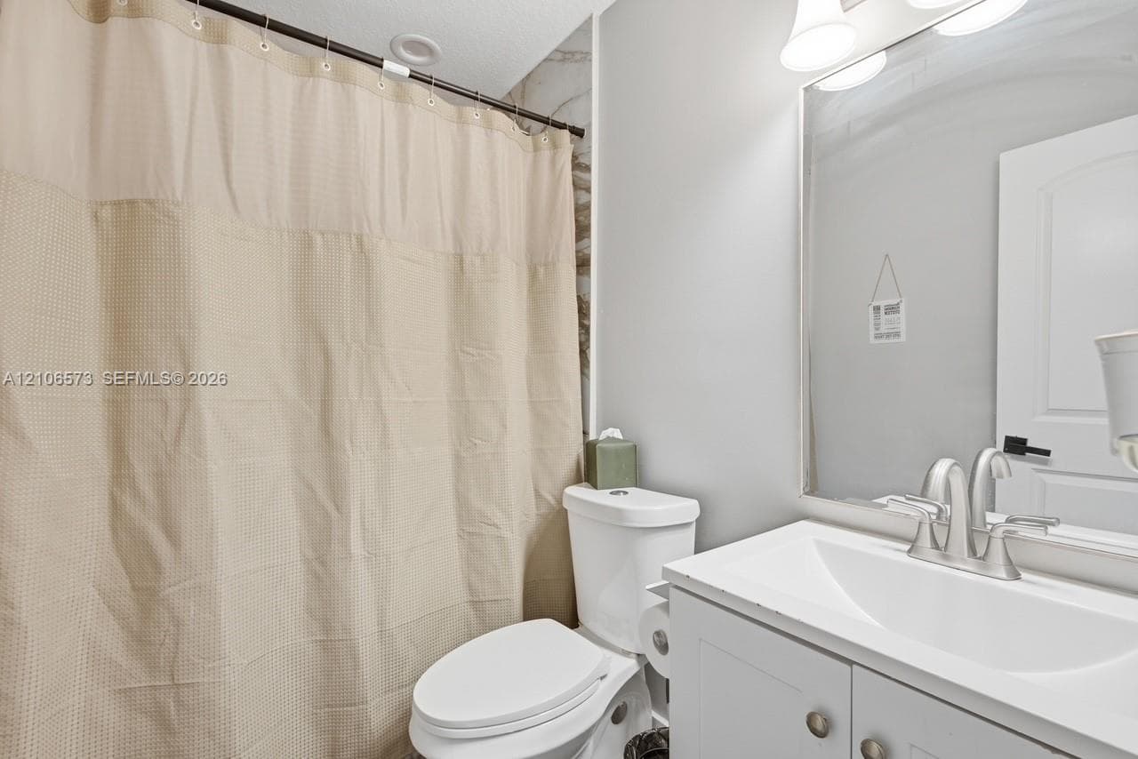 Bathroom featuring a white vanity cabinet with an integrated sink, polished chrome faucet, full-width mirror, and multi-bulb vanity lighting