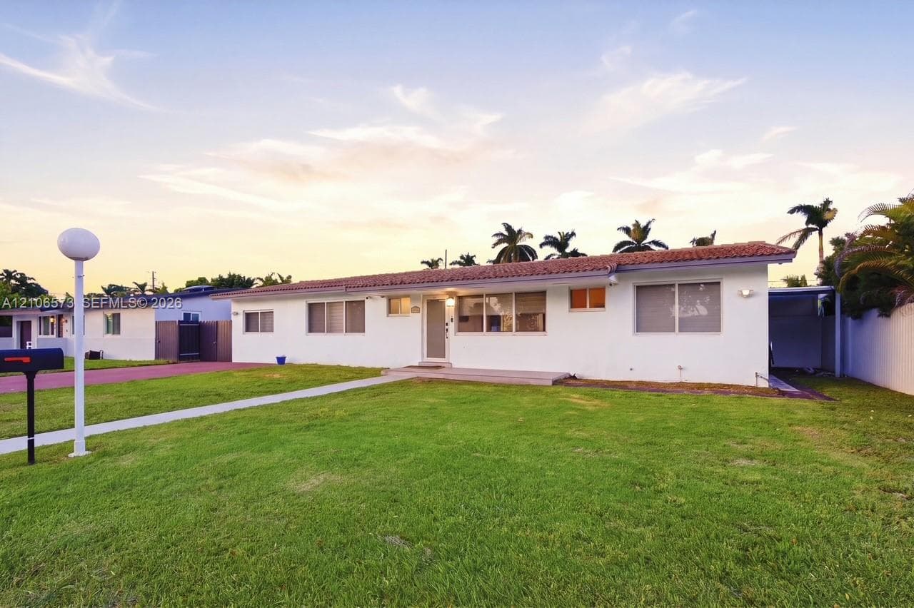 Single-story residence featuring a stucco exterior, clay tile roofing, expansive front lawn, and a paved driveway