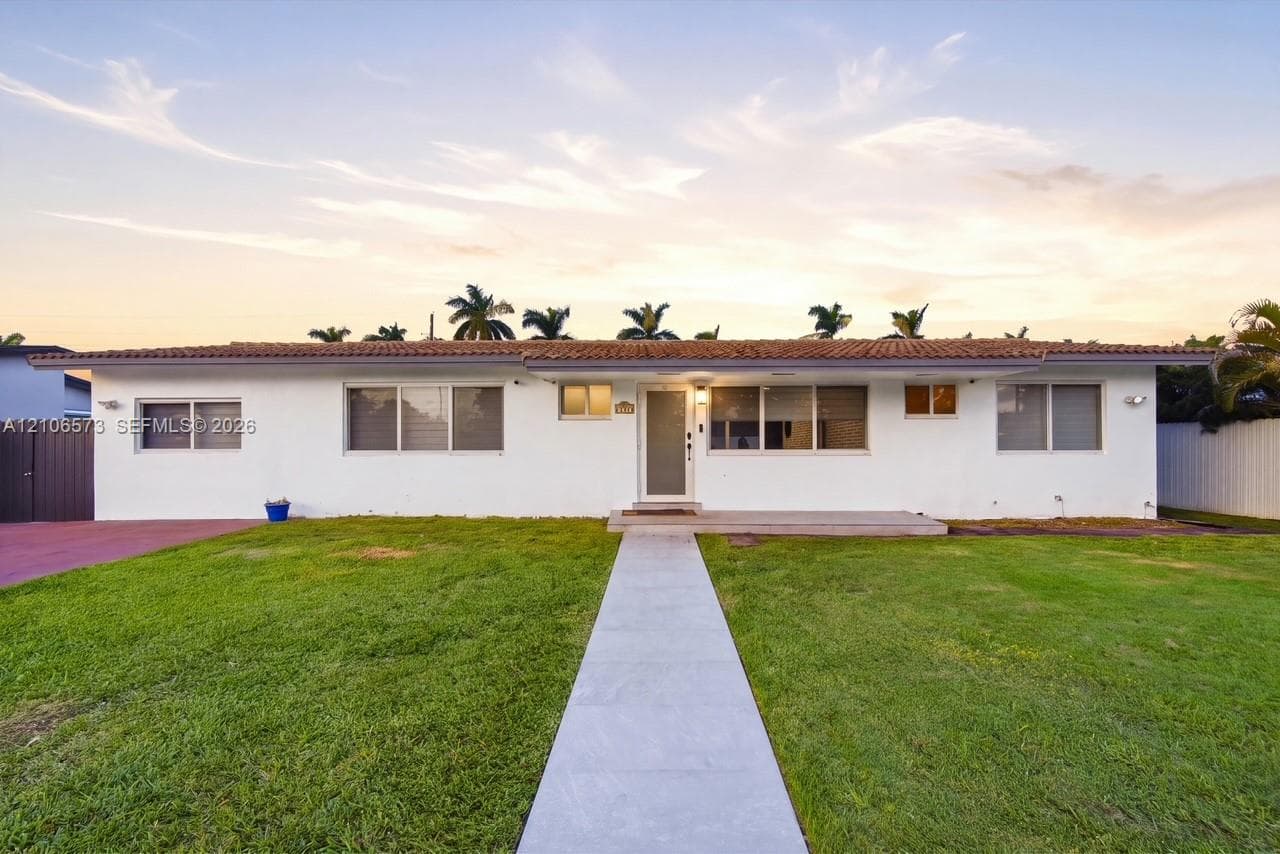 Single-story exterior featuring a low-pitched clay tile roof, white stucco facade, concrete walkway, and integrated front entry porch