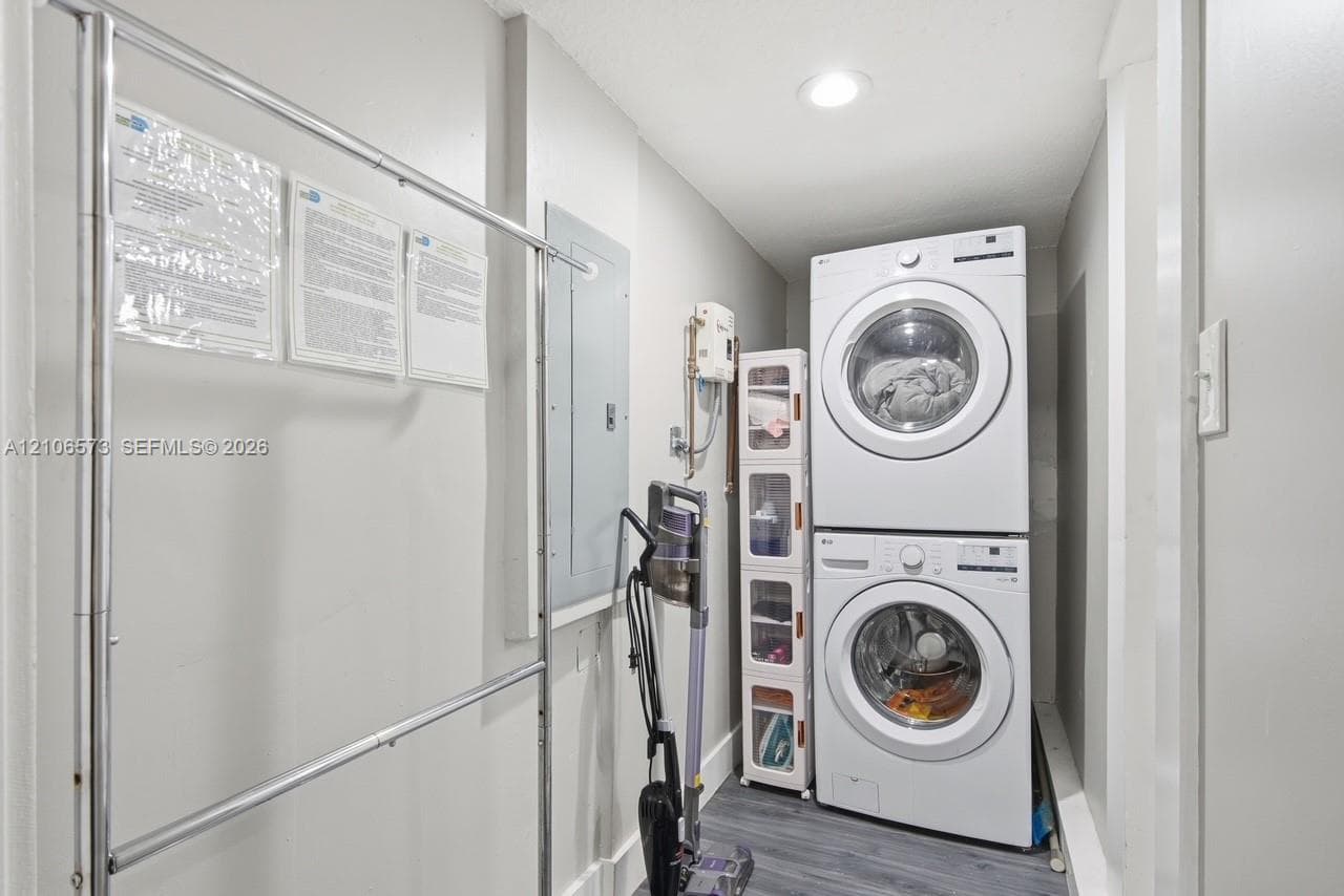 Laundry space featuring a stacked washer and dryer unit, recessed lighting, and wood-finish flooring