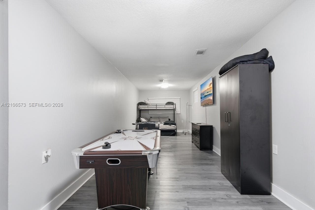 Neutral interior space featuring wood-finish flooring, light-colored walls, and a ceiling-mounted light fixture