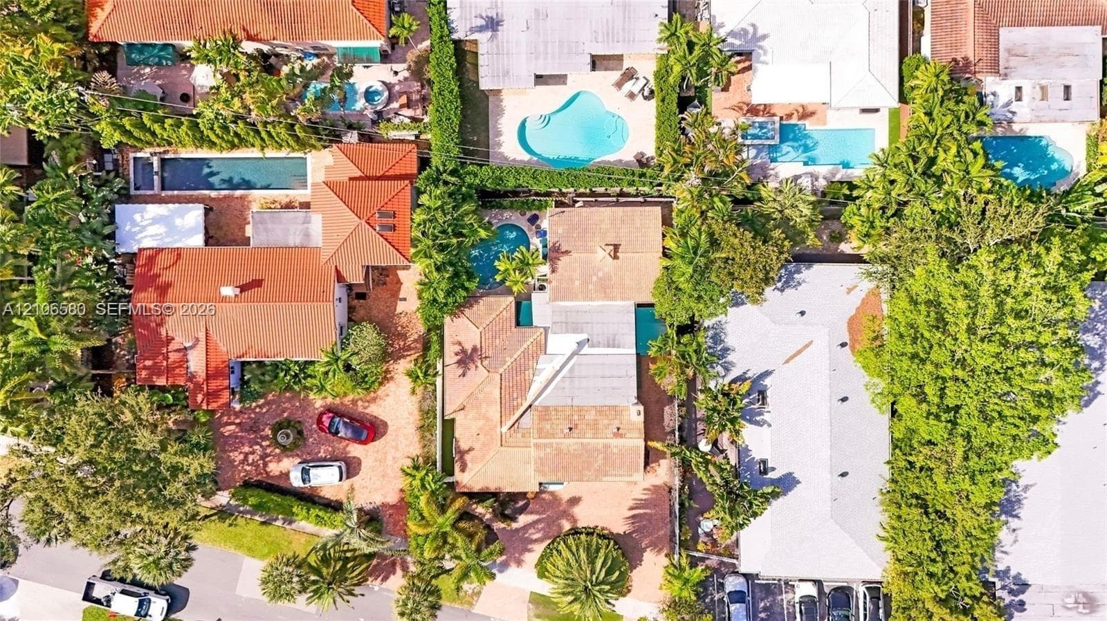 Aerial view of the property featuring a tile roof, an in-ground swimming pool, and a paved driveway
