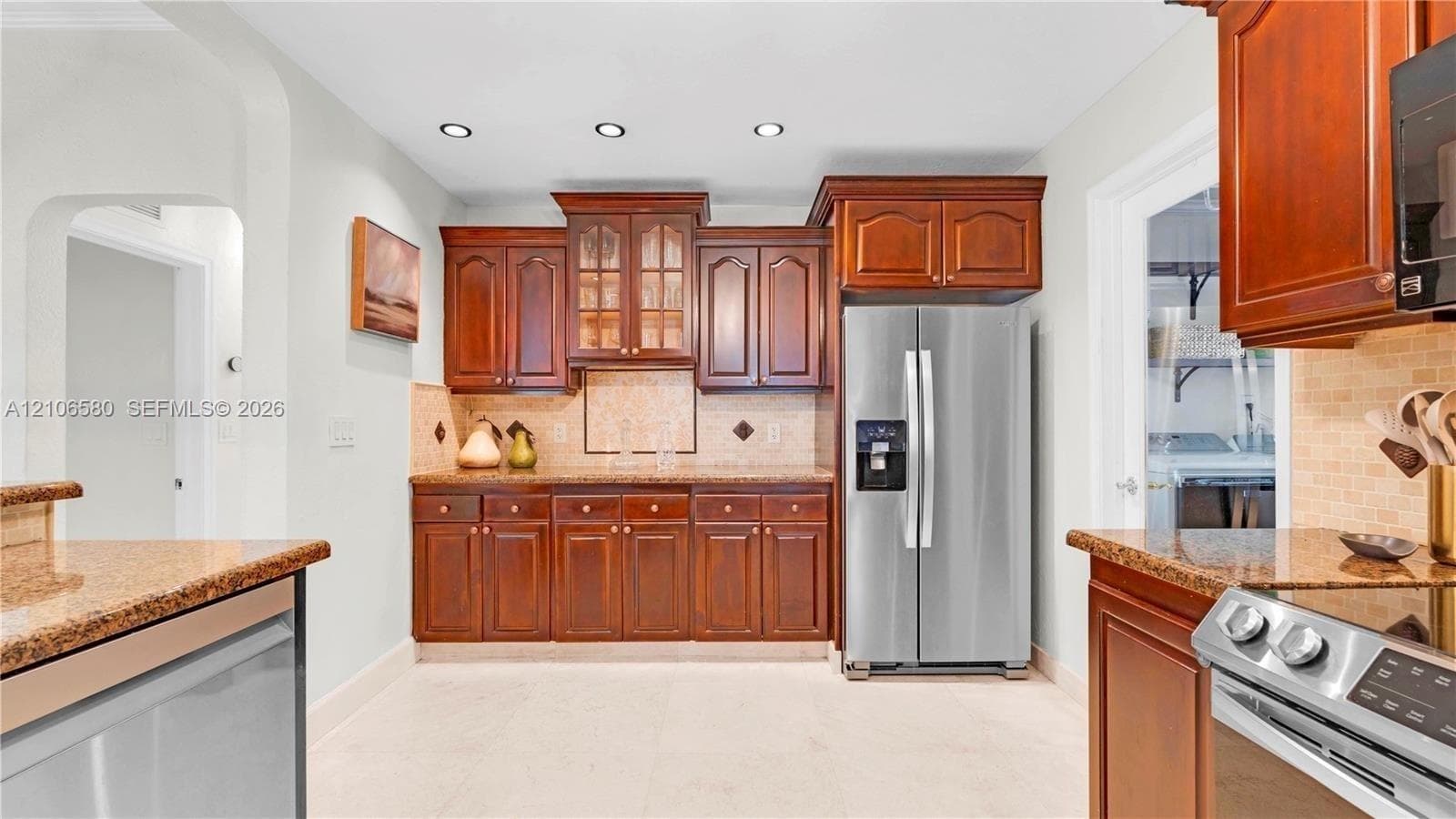 Kitchen featuring rich wood cabinetry, stone countertops, tiled backsplash, stainless steel appliances, and recessed lighting