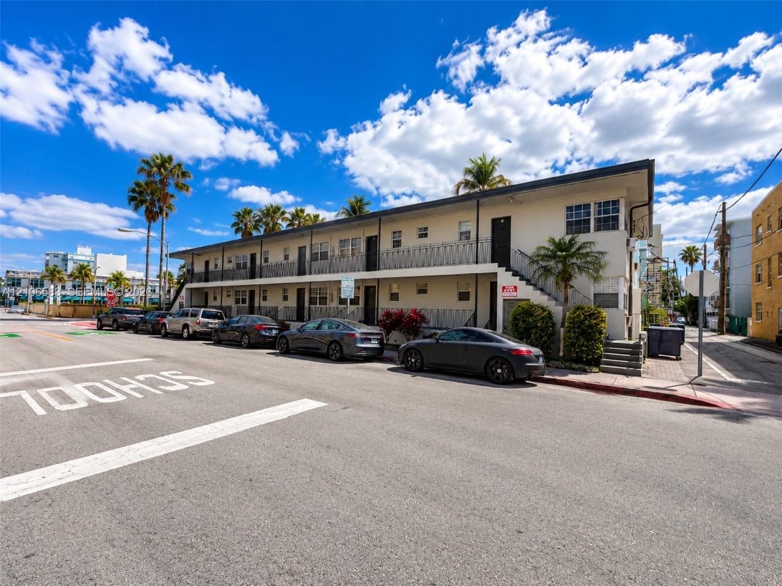 Two-story exterior featuring a flat roofline, stucco facade, decorative metal balcony railings, and exterior staircase