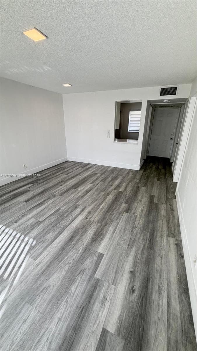 Wood-finish flooring, neutral walls, recessed lighting, and a pass-through wall opening