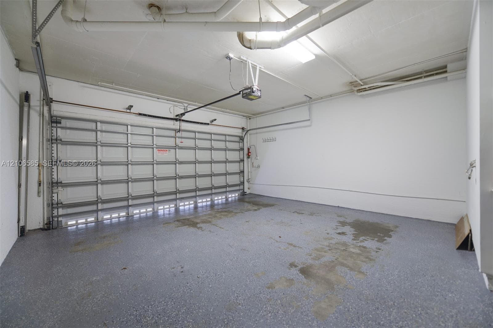 Multi-car garage featuring a sectional overhead door, epoxy-coated flooring, and overhead lighting