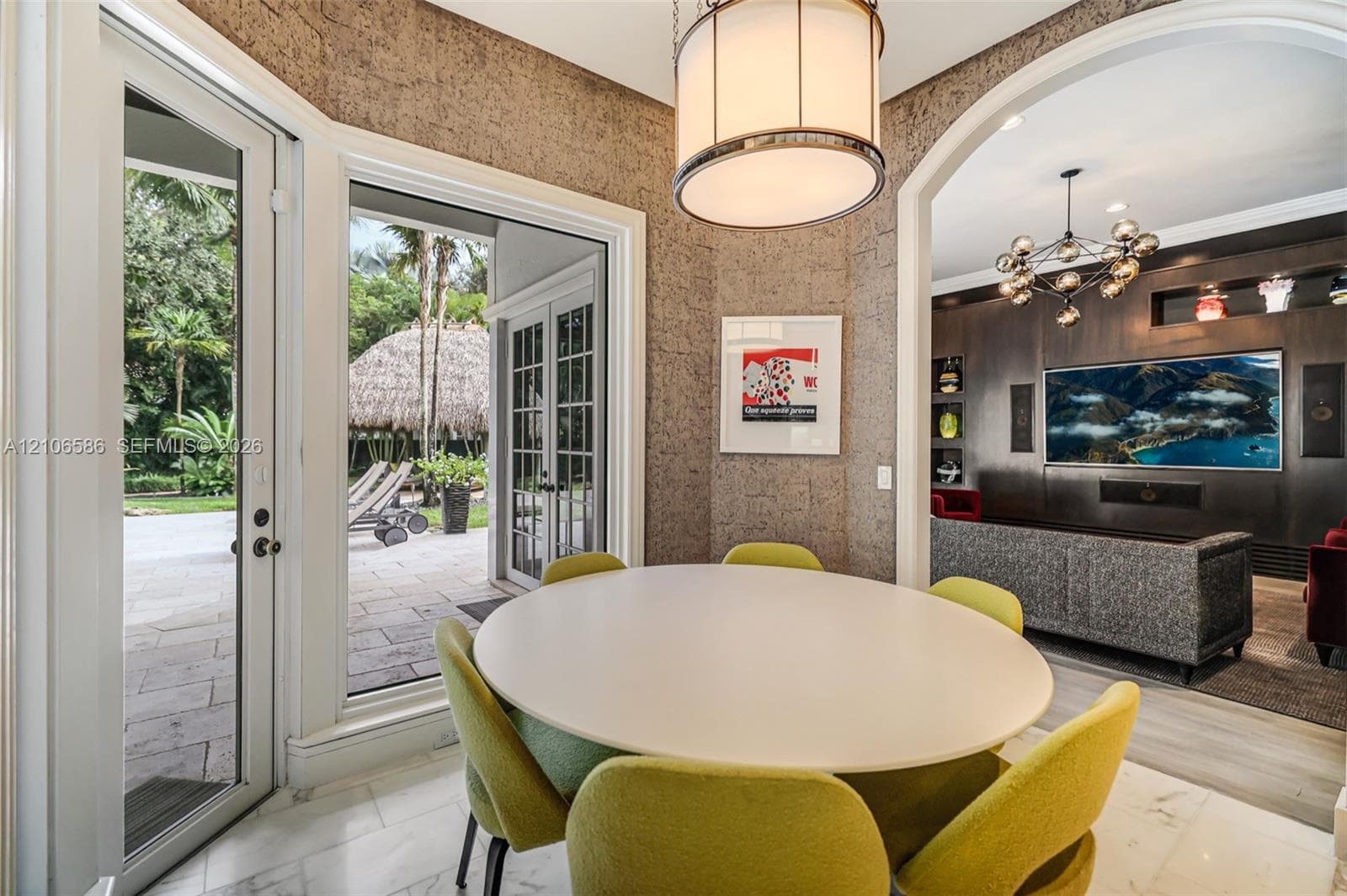 Dining area featuring textured wall coverings, stone-finish flooring, a contemporary drum pendant light, and French doors opening to an exterior patio