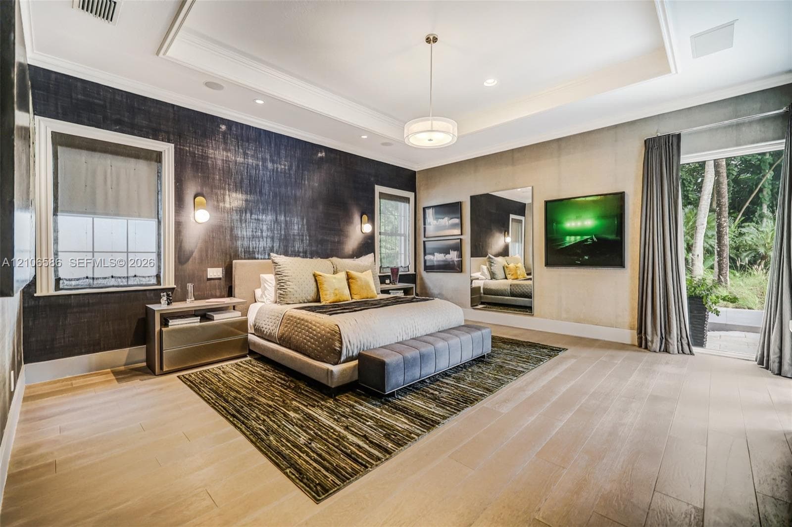 Tray ceiling with recessed lighting, wood-finish flooring, textured wall covering, wall-mounted accent lighting, and glass door entry to exterior space
