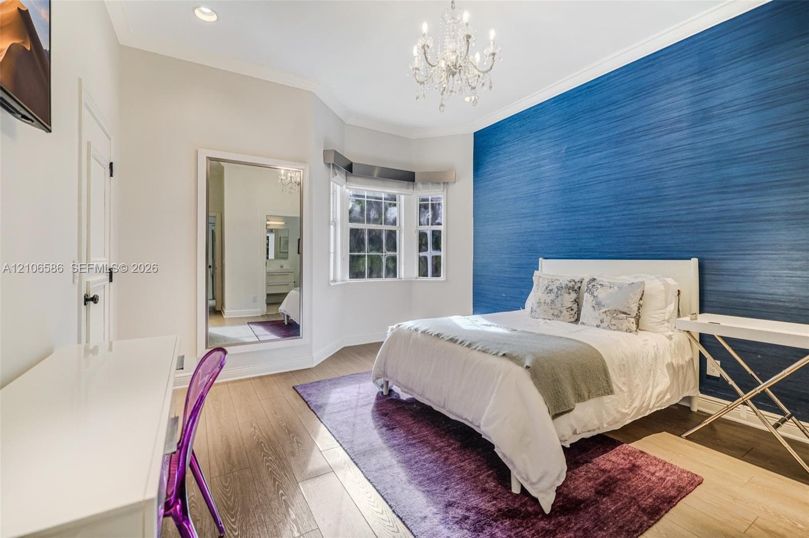 Bedroom featuring a deep blue textured accent wall, bay window, wood-finish flooring, recessed lighting, and a crystal chandelier