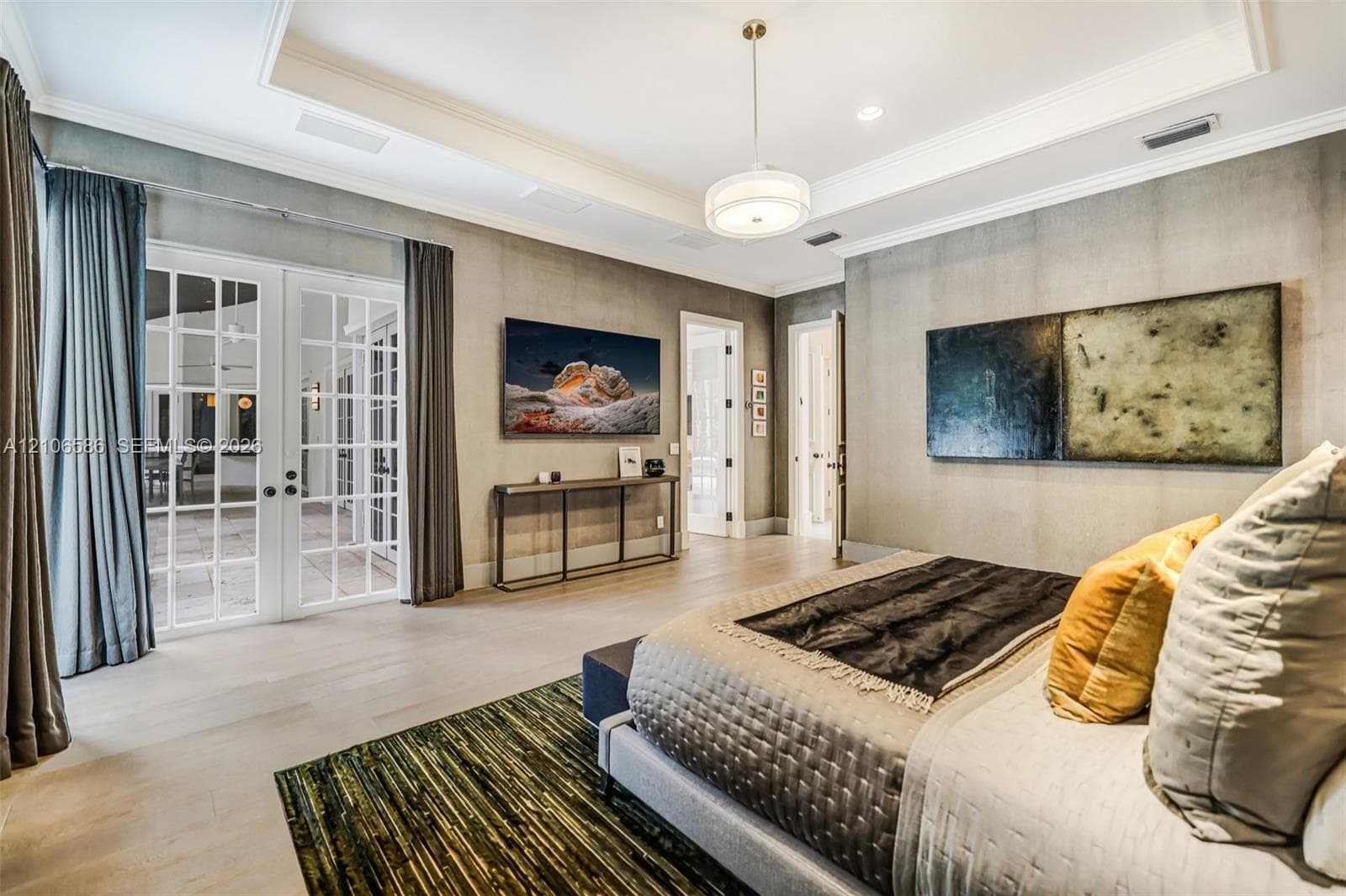 Tray ceiling with crown molding, double French doors with glass panes, wood-finish flooring, and recessed lighting