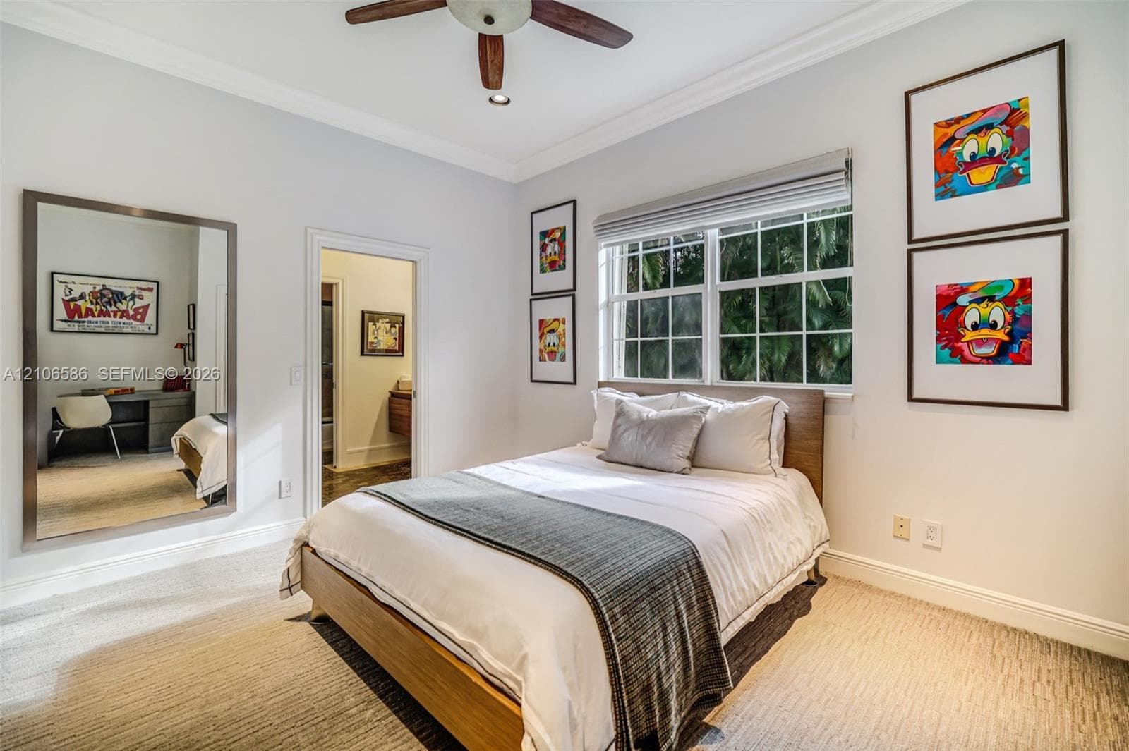 Room featuring neutral carpeting, crown molding, multi-pane window with custom blinds, ceiling fan, and a large wall-mounted mirror