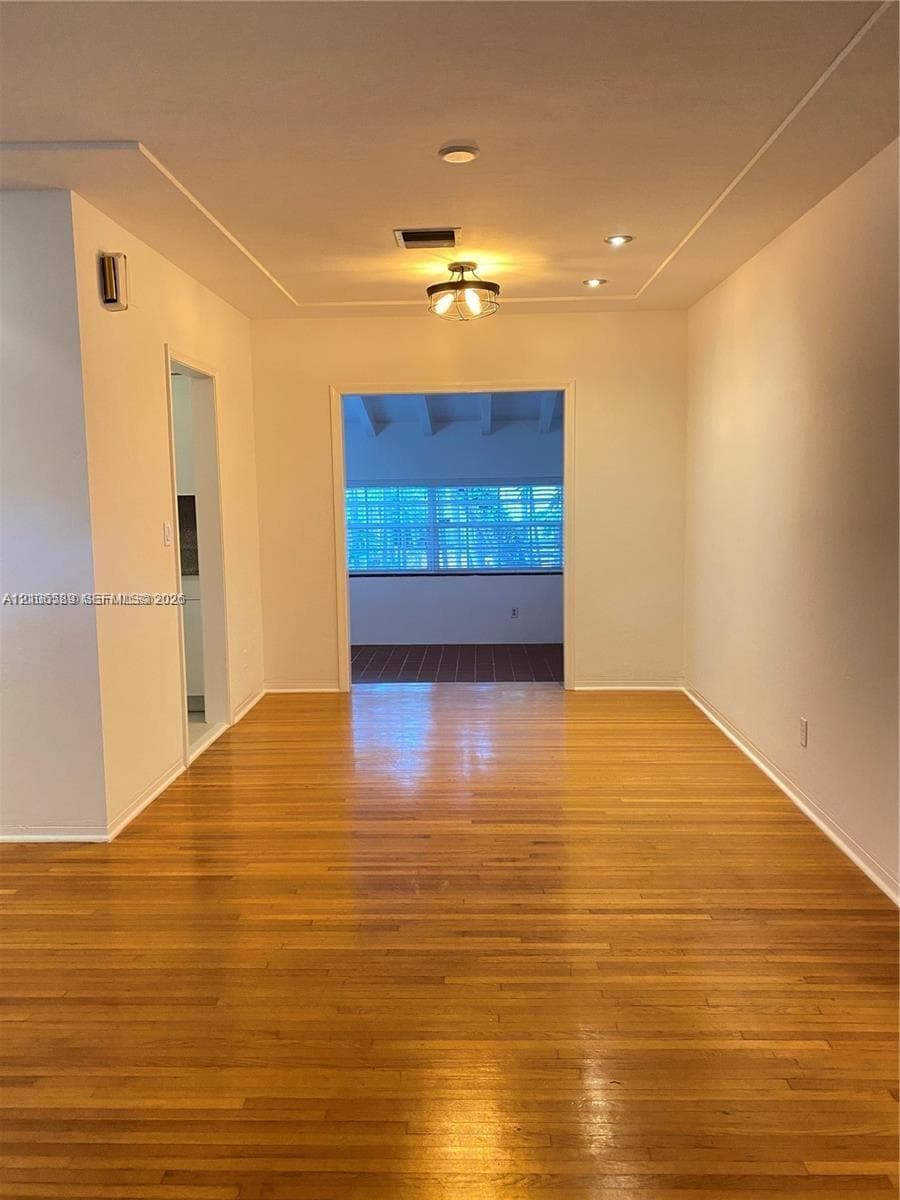 Interior space featuring wood-finish flooring, recessed lighting, a decorative ceiling-mounted fixture, and a tray ceiling detail