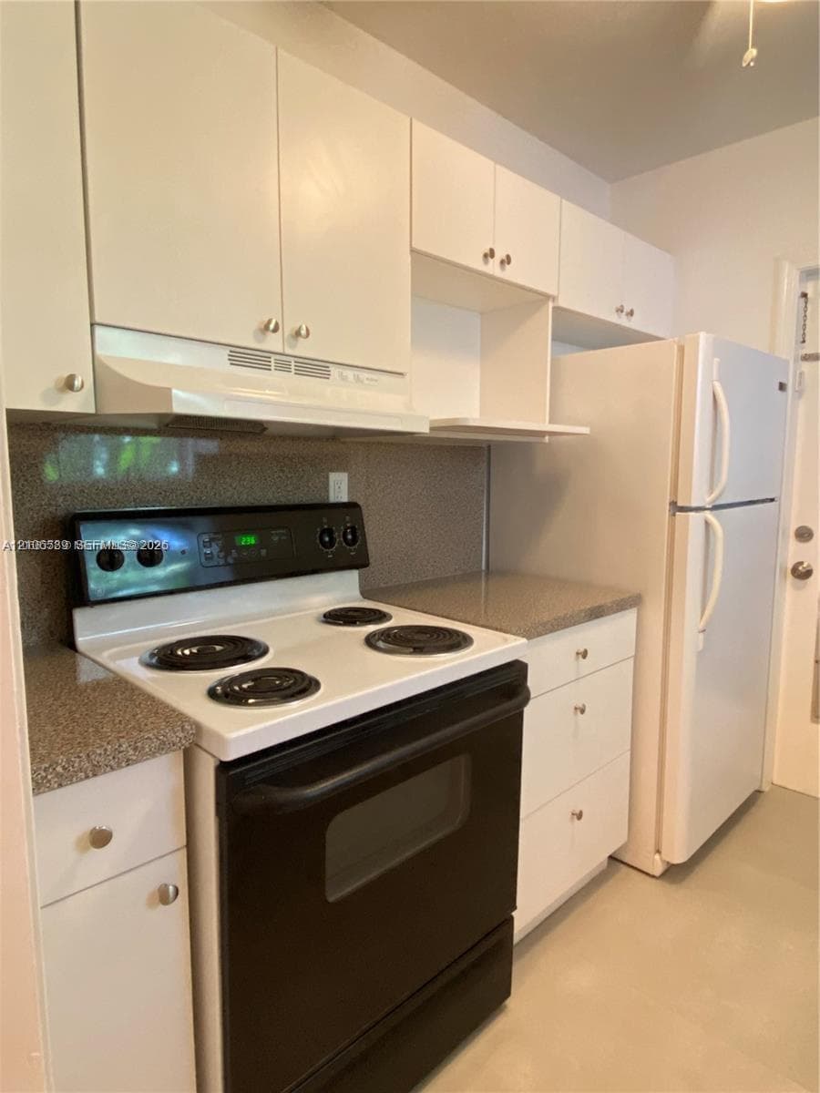 Kitchen featuring white cabinetry, speckled laminate countertops, a black electric range, a white refrigerator, and a coordinating range hood