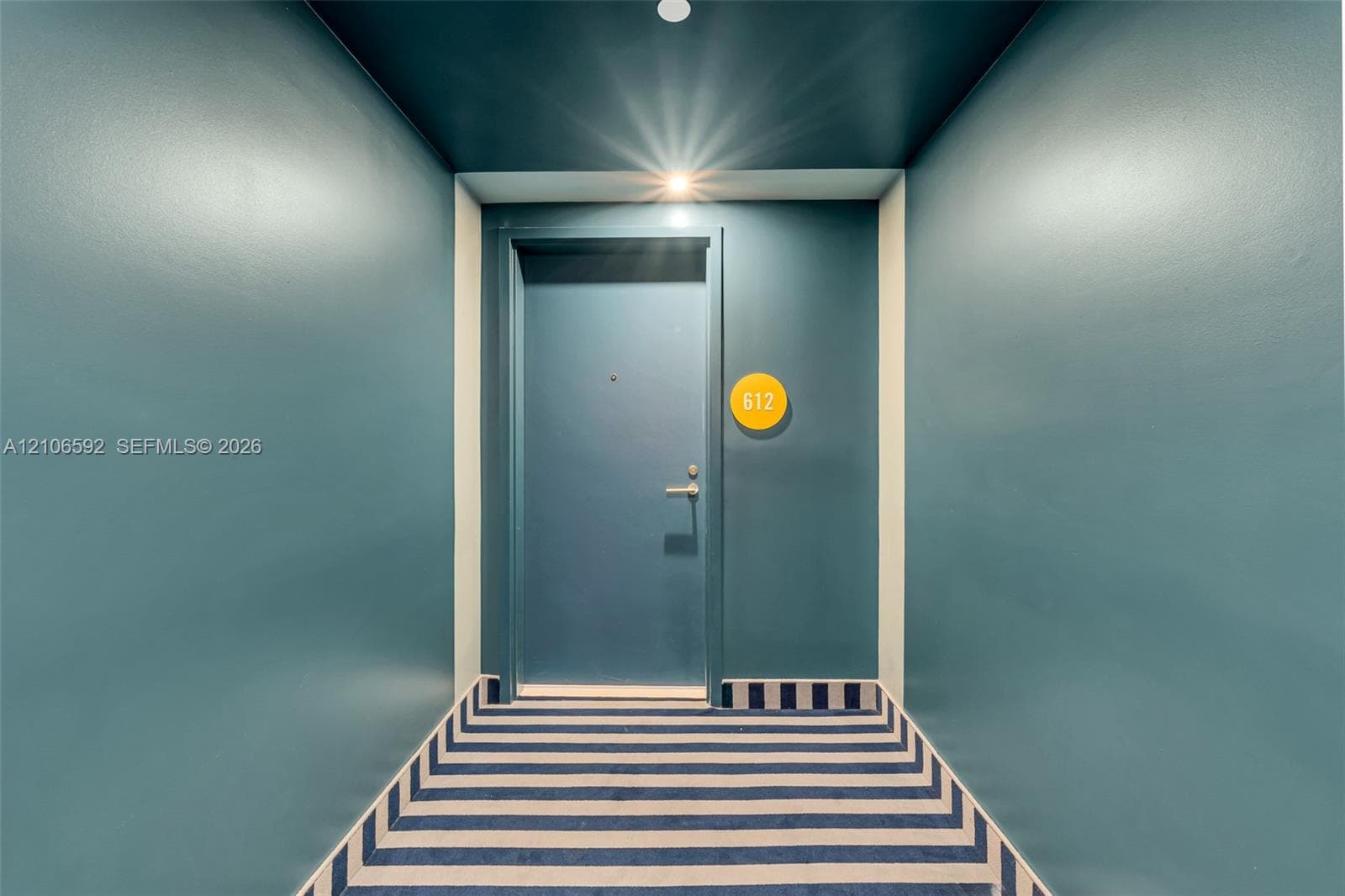 Entryway featuring saturated wall paint, a recessed ceiling light, a solid door with metallic hardware, and a striped carpet runner