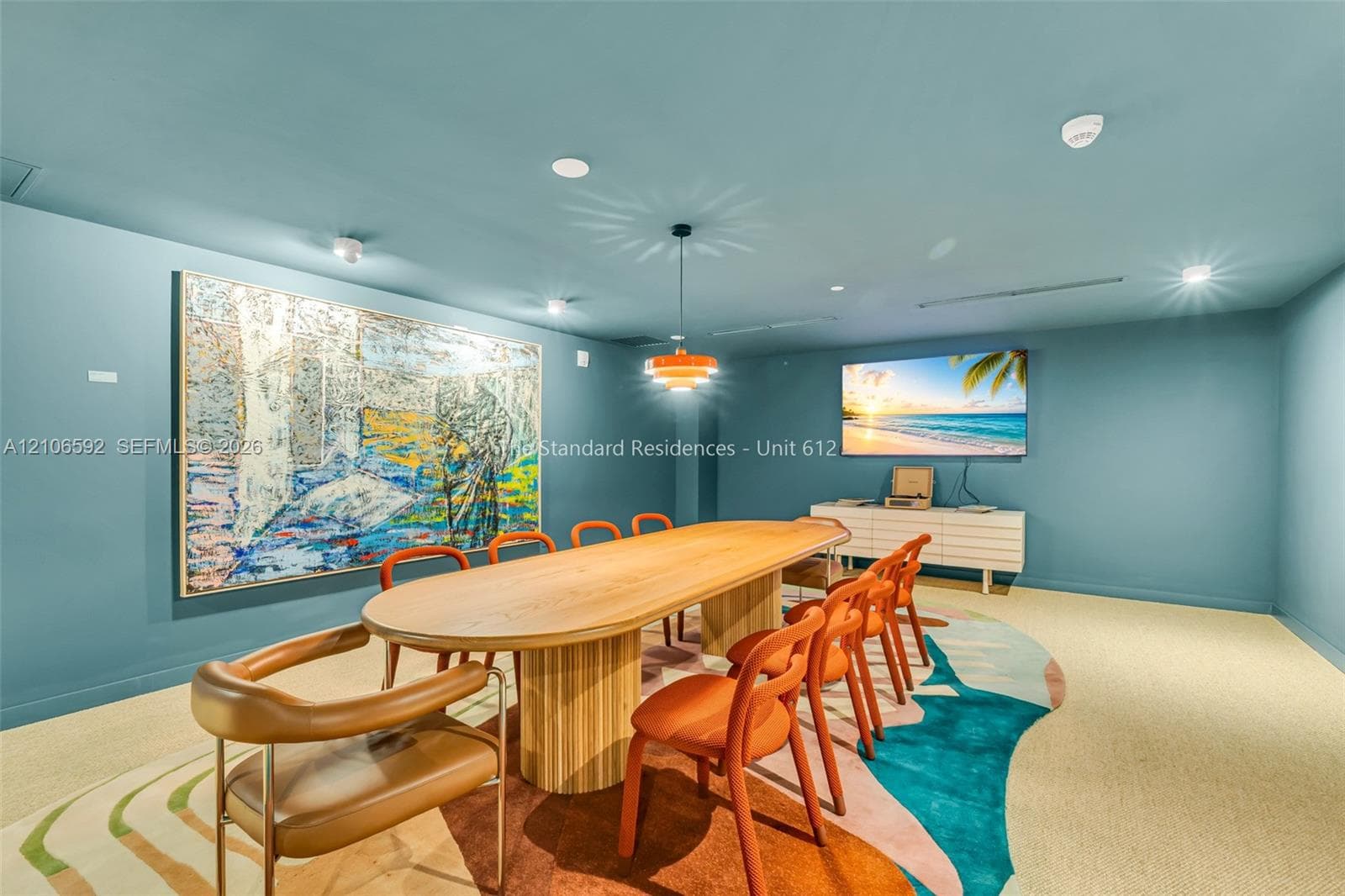 Multi-purpose space featuring recessed ceiling lighting, a modern tiered pendant fixture, and neutral wall-to-wall carpeting