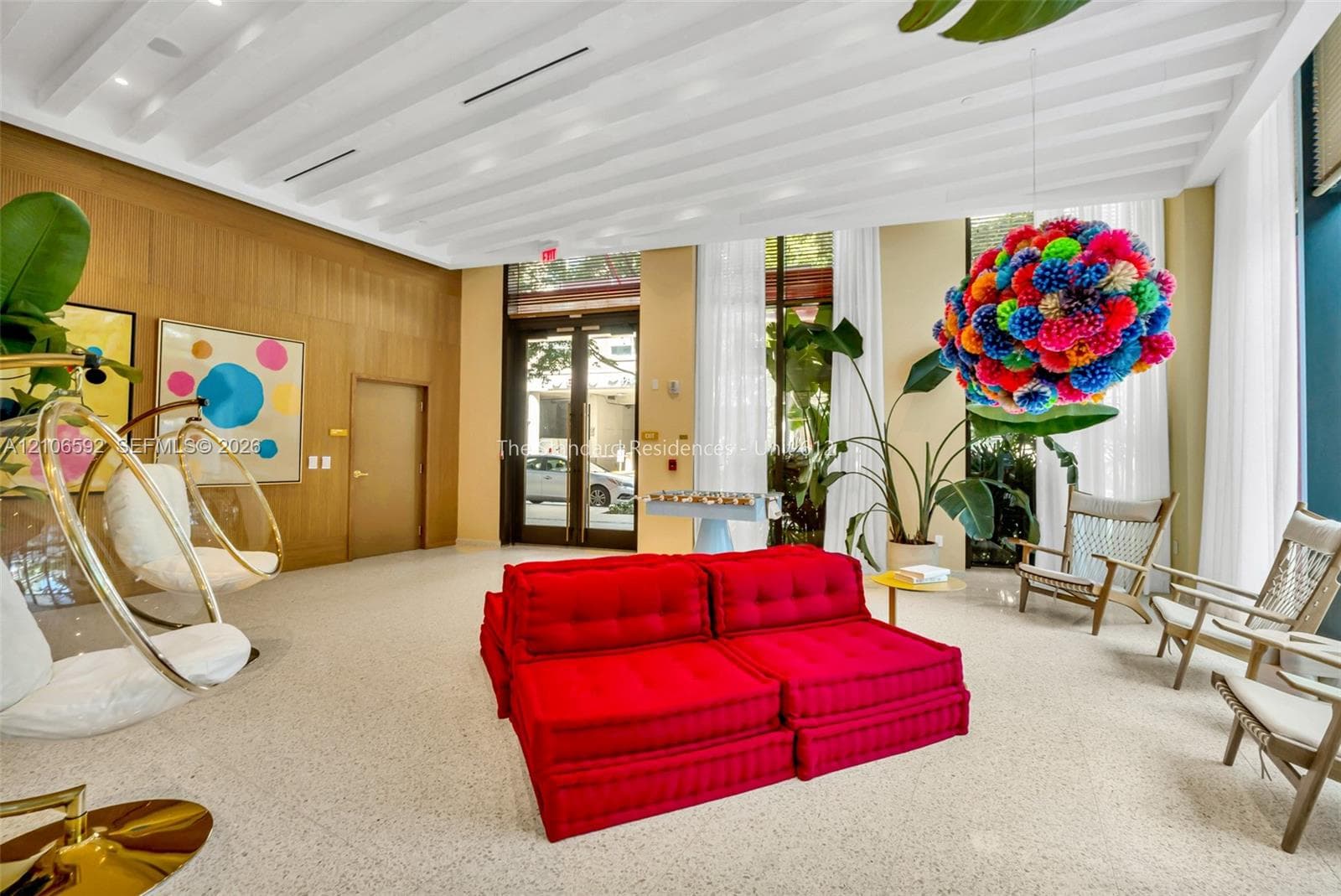 High-ceiling lobby featuring expansive floor-to-ceiling windows, light-toned terrazzo flooring, and natural wood-paneled walls