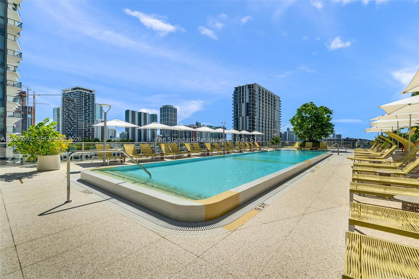 Rooftop swimming pool featuring a tiled perimeter, integrated drainage, glass panel railings, and expansive paved deck surfacing