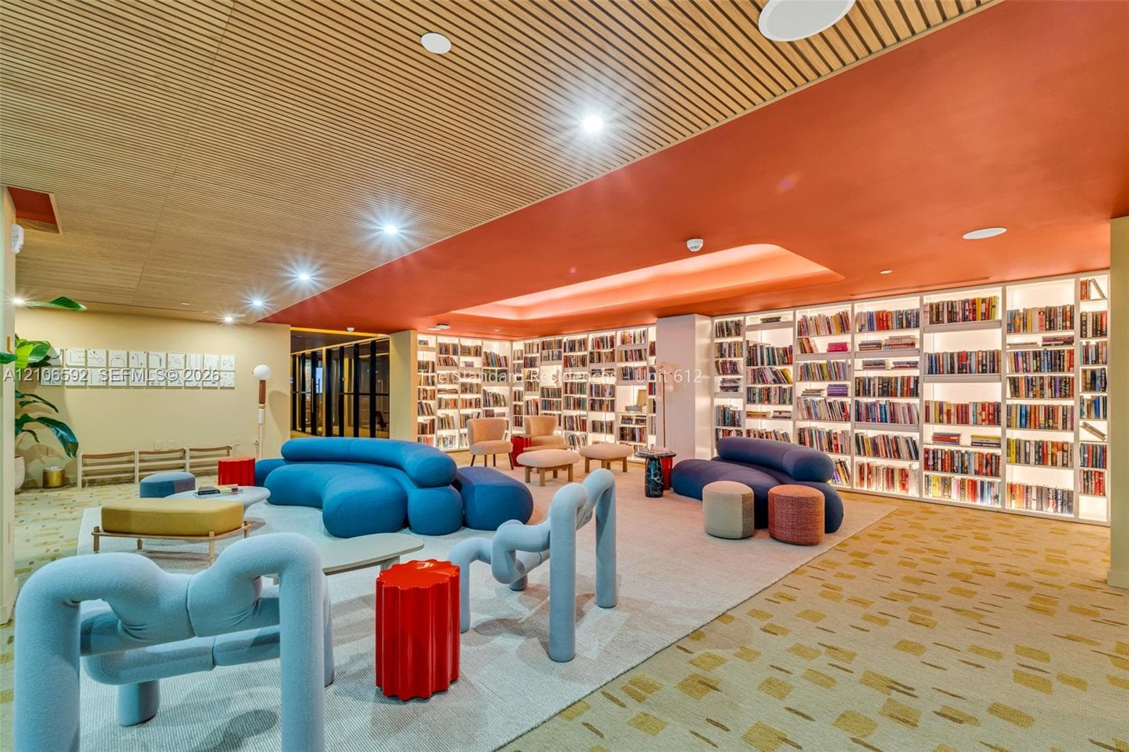 Custom floor-to-ceiling built-in shelving, slatted wood-finish ceiling, recessed lighting, and patterned carpeting