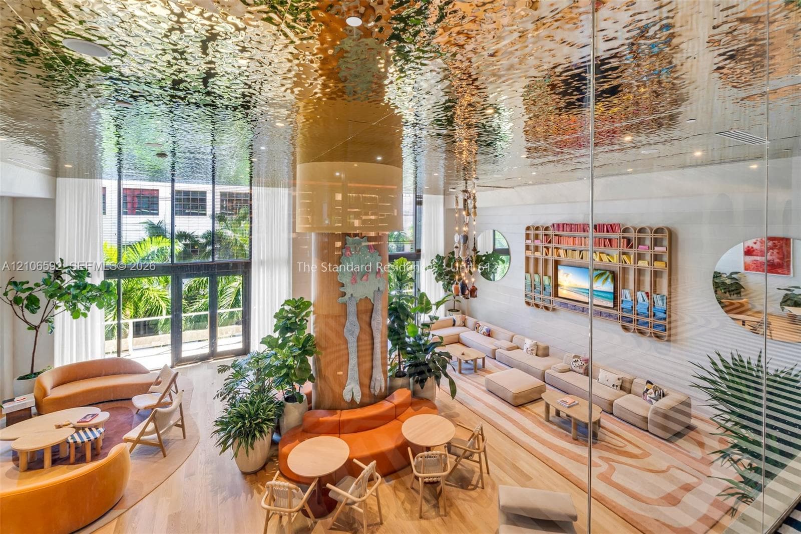 Common area featuring a reflective, textured metallic ceiling, floor-to-ceiling glass windows, wood-finish flooring, and a large custom built-in wall unit