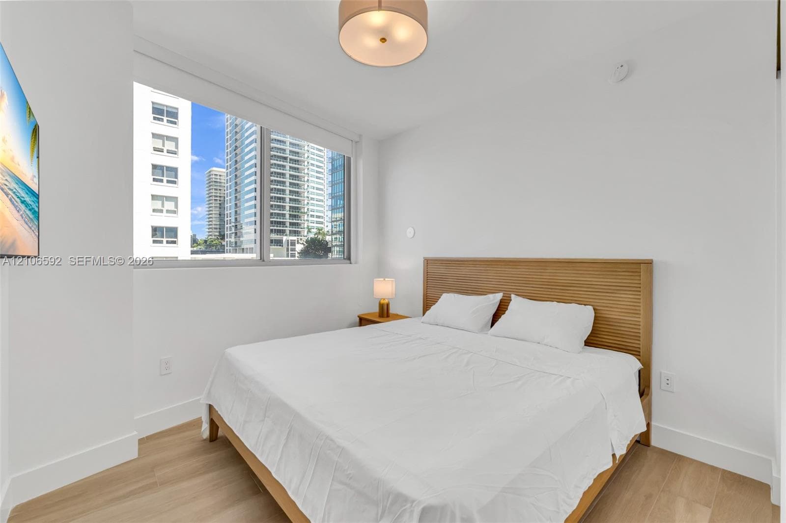 Large windows, light wood-finish flooring, and a contemporary drum-style ceiling light fixture