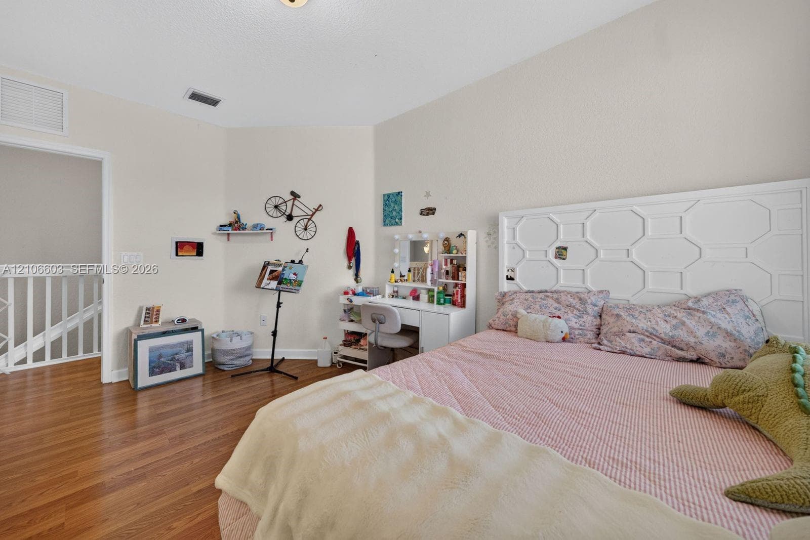 Bedroom featuring wood-finish flooring, textured walls, and a white geometric-patterned headboard