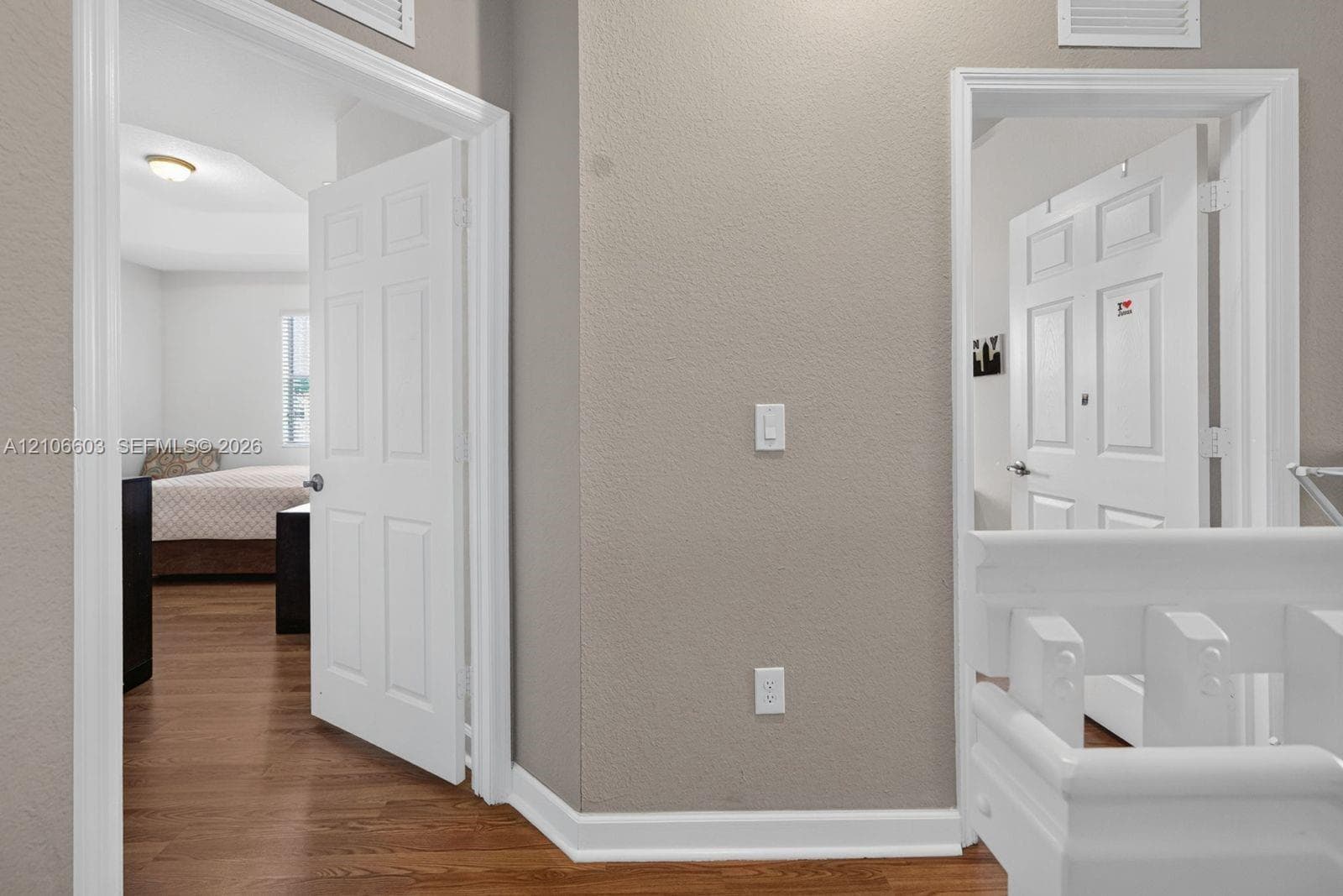 Interior hallway featuring neutral wall finishes, white six-panel interior doors, and wood-finish flooring