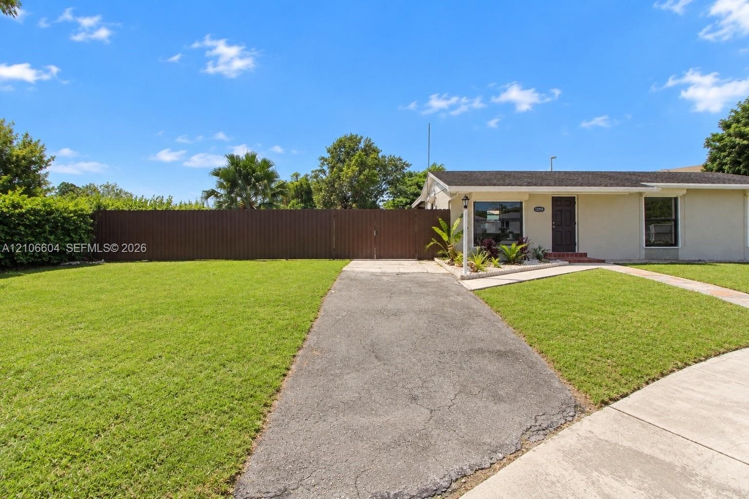 Single-story residence featuring a front lawn, paved driveway, and perimeter privacy fencing
