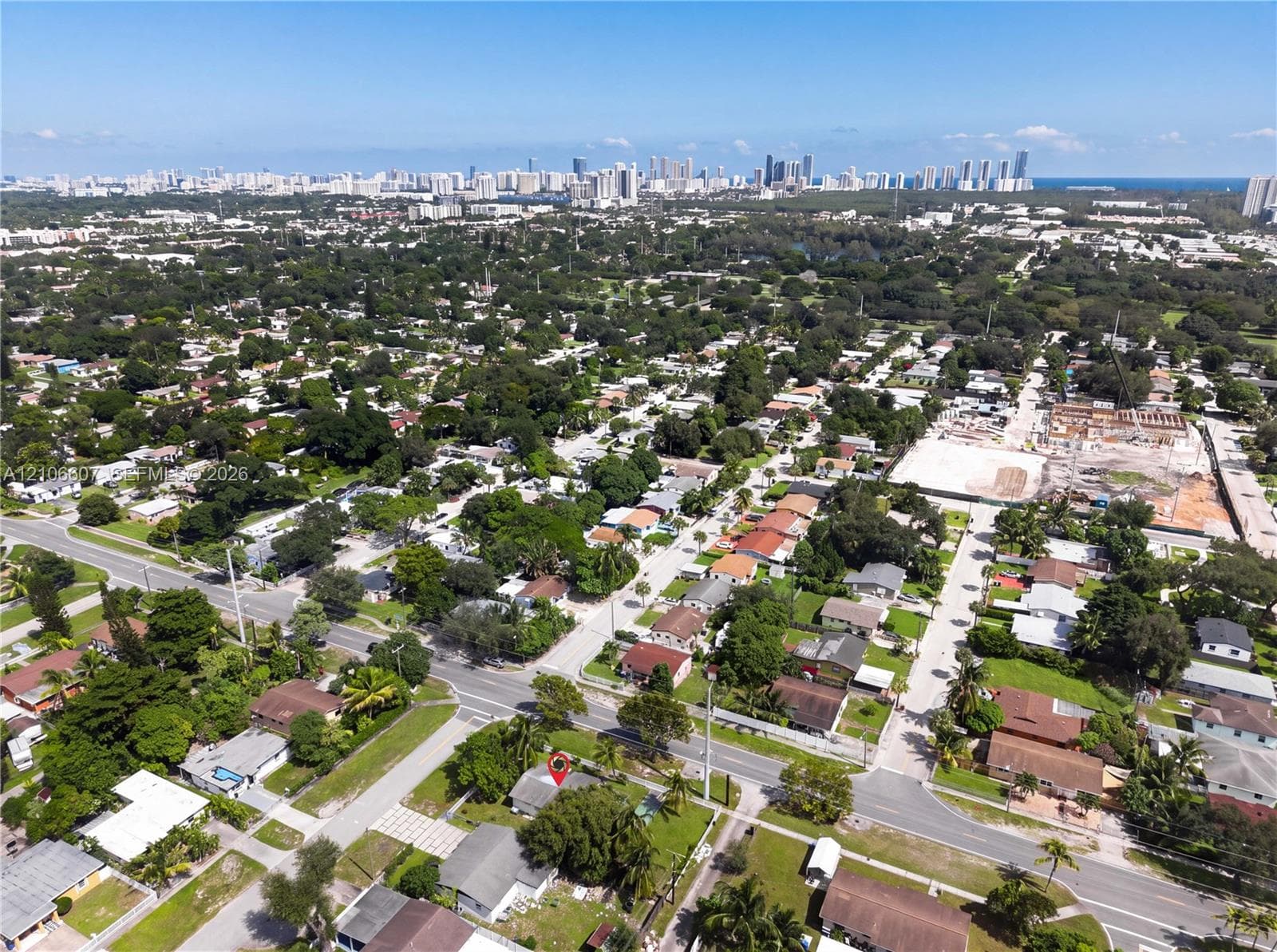 Aerial perspective of a residential lot featuring mature trees and a prominent city skyline backdrop