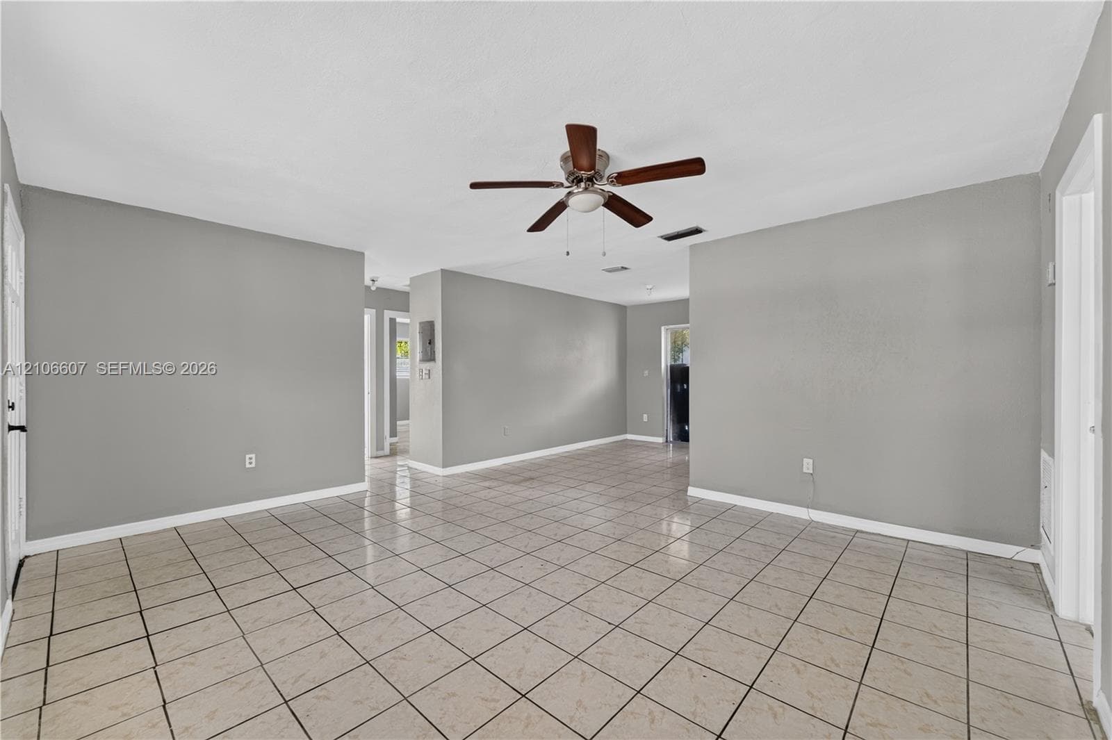 Interior space featuring neutral-toned walls, tile flooring, and a ceiling-mounted fan with integrated lighting