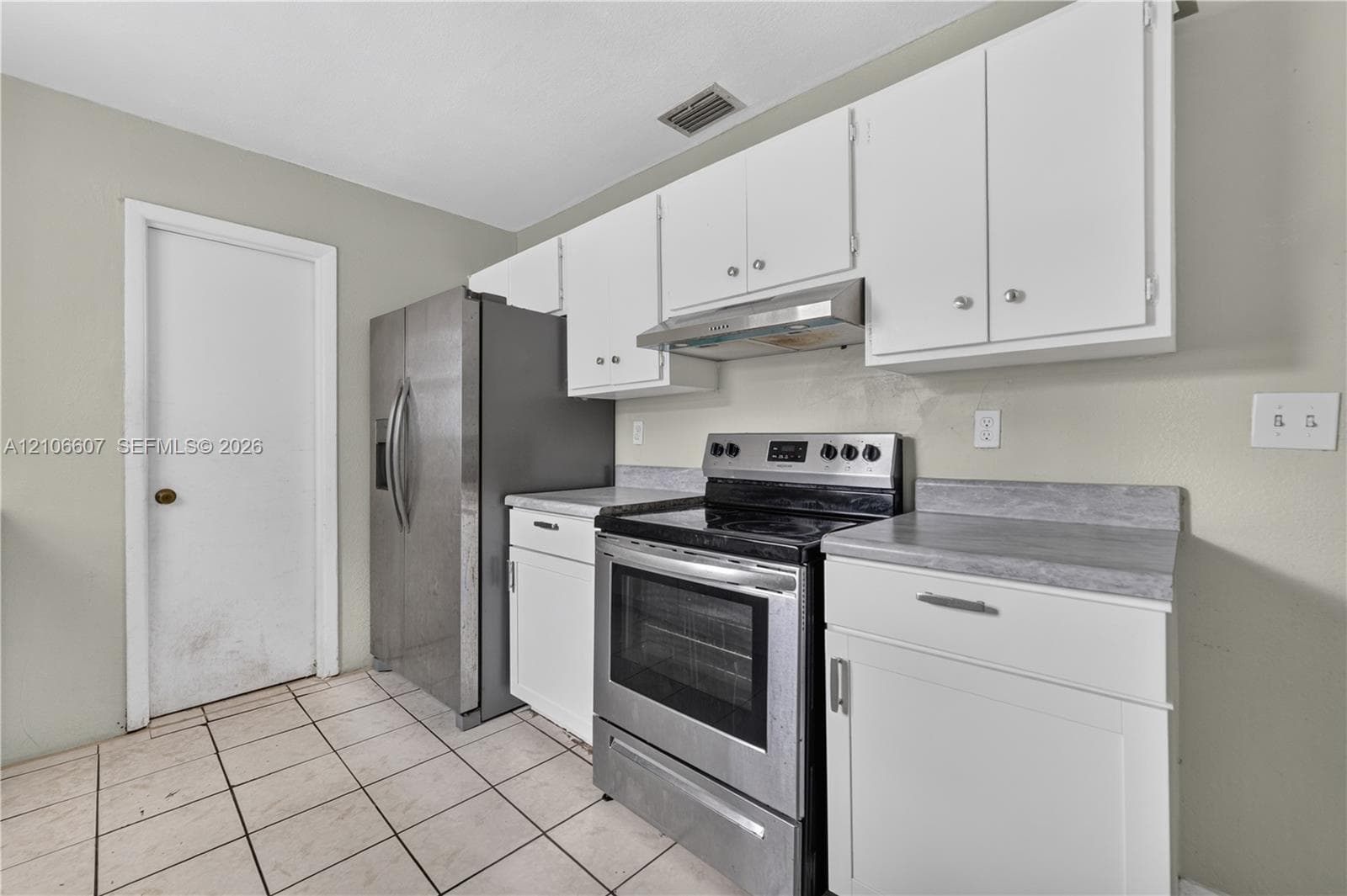 Kitchen featuring white cabinetry, stone-finish countertops, stainless steel appliances, and tiled flooring