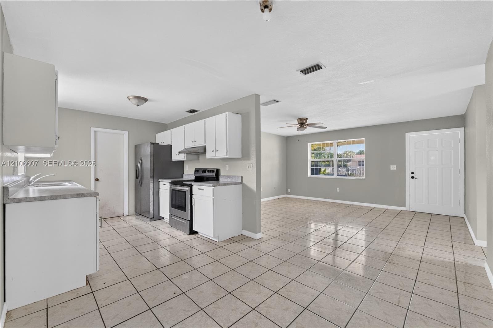 Kitchen featuring white cabinetry, stainless steel refrigerator and range, tile flooring, and a window with natural light