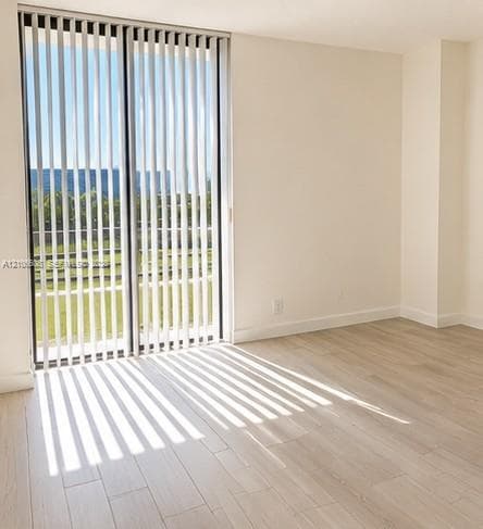 Floor-to-ceiling sliding glass doors with vertical blinds, light-toned wood-finish flooring, and neutral wall color