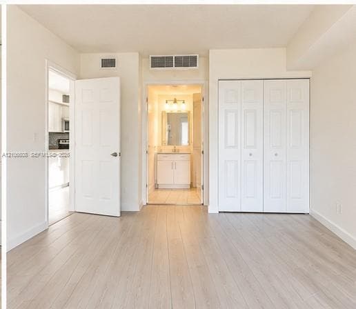 Neutral-toned wood-finish flooring, white paneled interior doors, and a double-door reach-in closet featuring raised-panel detailing