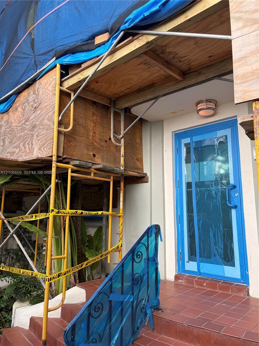 Entryway featuring a glass-panel door with blue metal framing, ceramic tile steps, and a flush-mount exterior light fixture