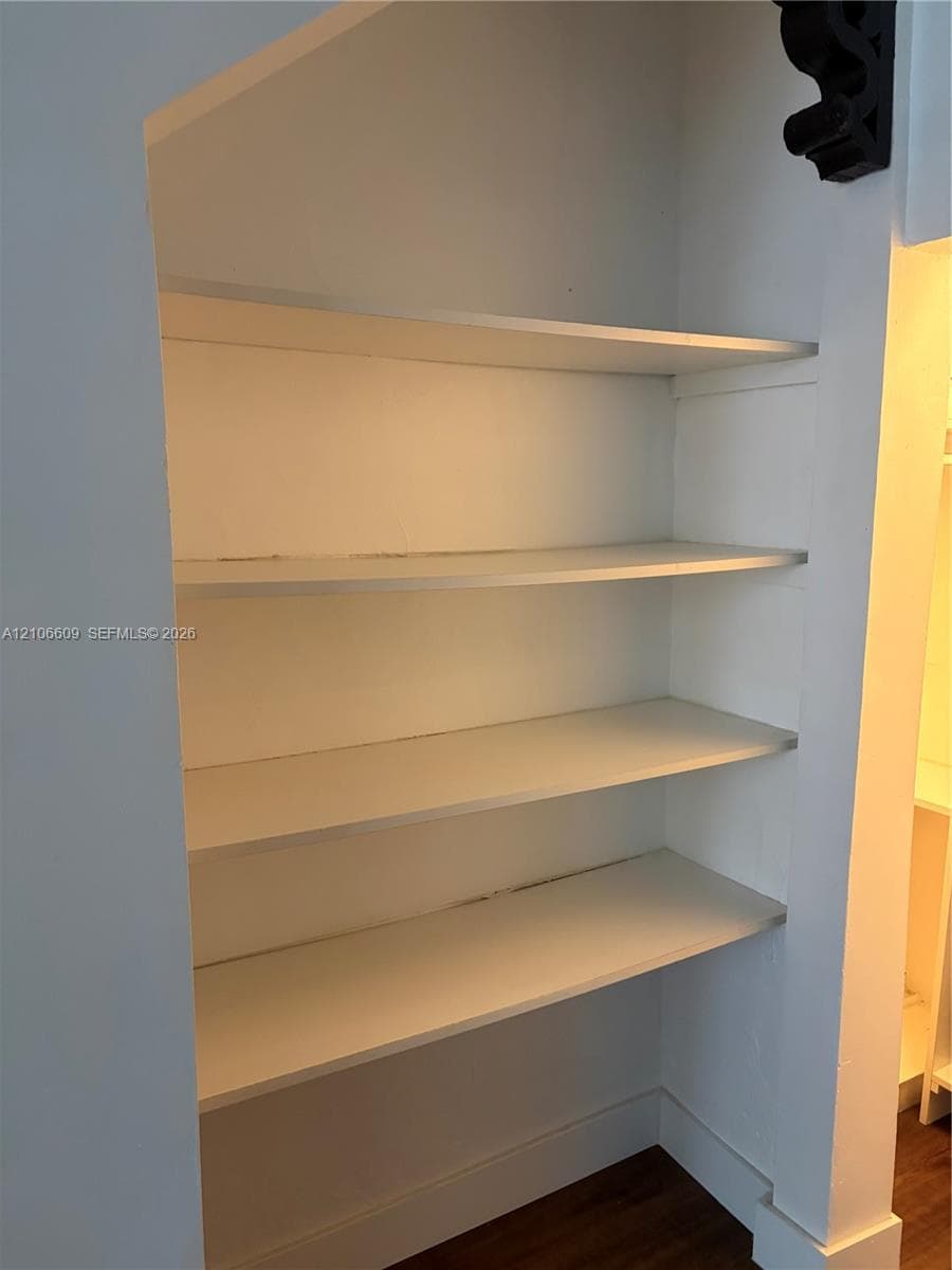 Built-in alcove featuring four recessed white shelving units and wood-finish flooring