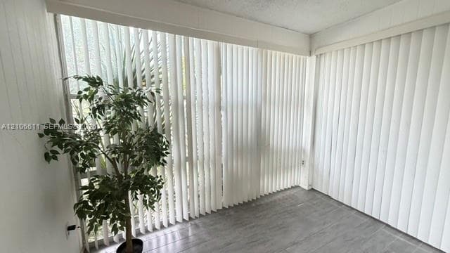 Floor-to-ceiling windows featuring vertical blinds and grey wood-finish flooring