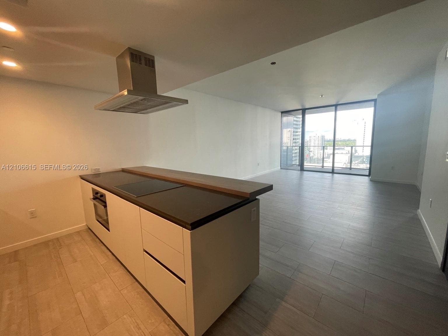 Kitchen featuring a center island with a cooktop, built-in wall oven, stainless steel range hood, and plank-style flooring throughout