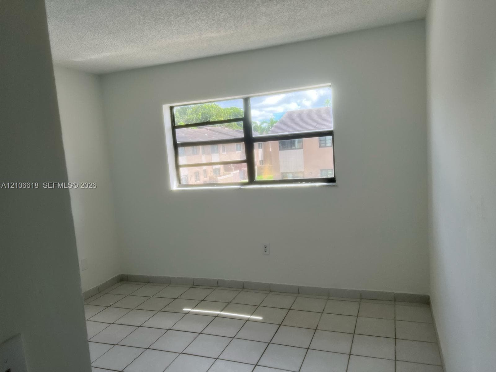 Interior room featuring ceramic tile flooring, neutral wall finishes, and a multi-pane window with dark frames