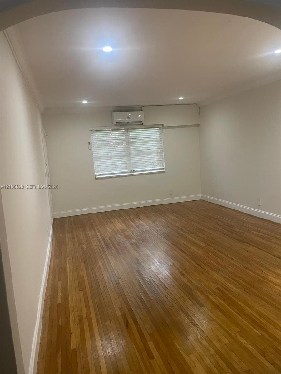 Interior space featuring wood-finish flooring, recessed lighting, and a wall-mounted climate control unit
