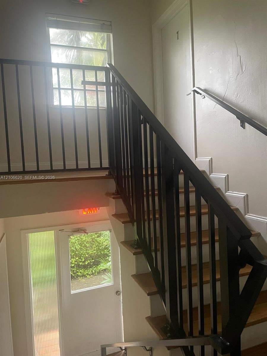 Staircase featuring wood-finish treads, matte black metal railings, and a window with horizontal blinds
