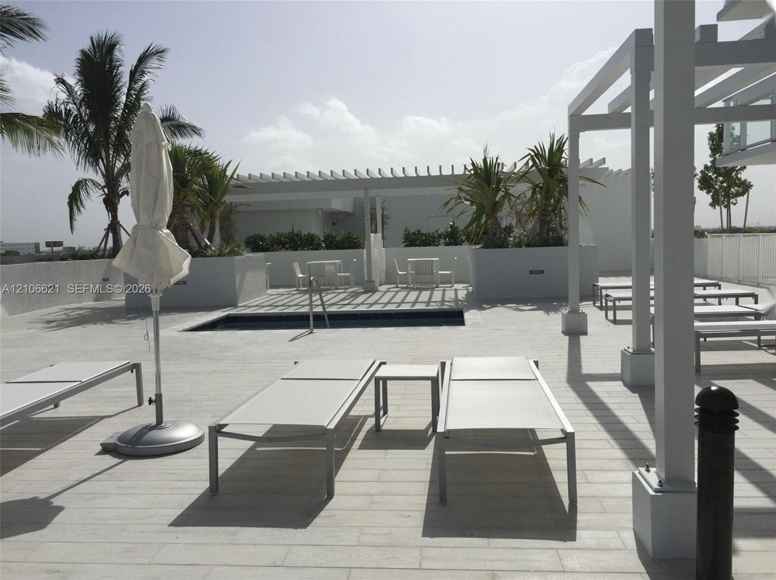 Rooftop terrace featuring light-toned tiling, a built-in plunge pool, custom-built white pergolas, and integrated concrete planters