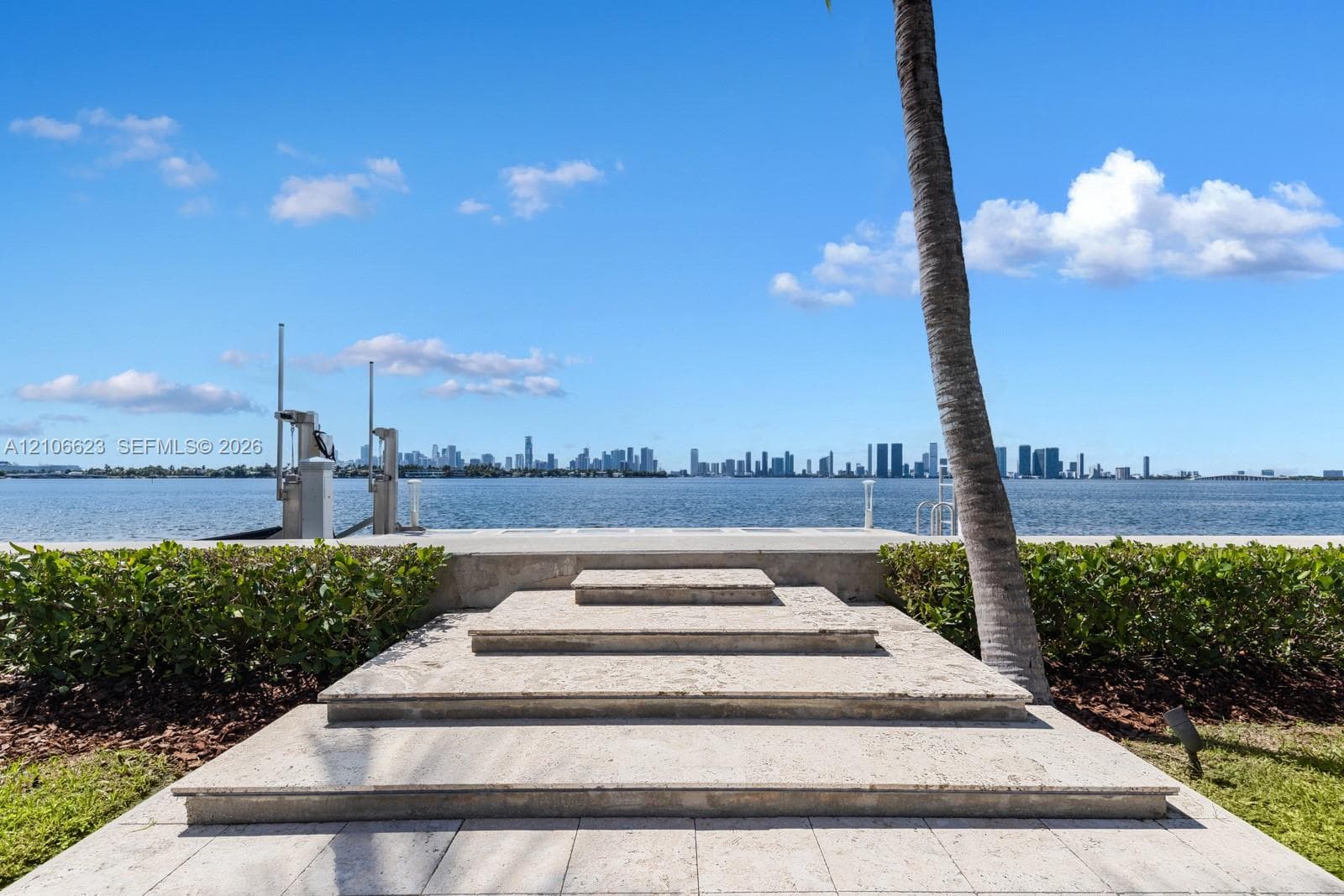 Stone-paved steps leading to a concrete seawall with a private boat lift and direct water frontage