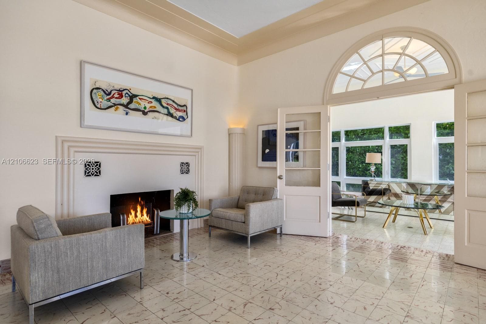 Fireplace with custom molding, high-gloss tile flooring, arched fanlight transom window, glass-paned French doors, and elevated tray ceilings