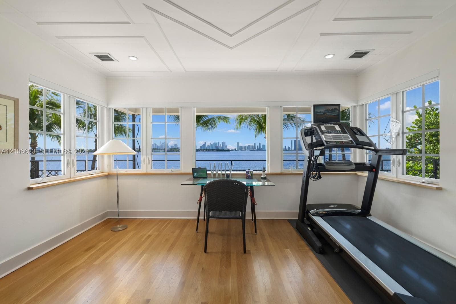 Multi-pane windows, wood-finish flooring, recessed lighting, and geometric coffered ceiling detail, with expansive water and skyline exposure
